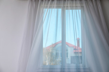 Window with fluttering curtain indoors. Home interior