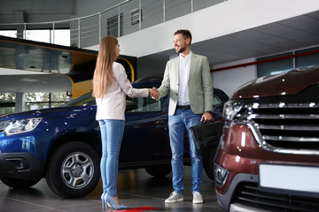 Customer and salesperson shaking hands in car dealership