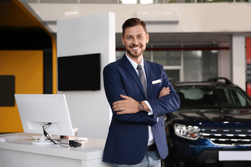 Salesman standing in modern auto dealership. Buying new car