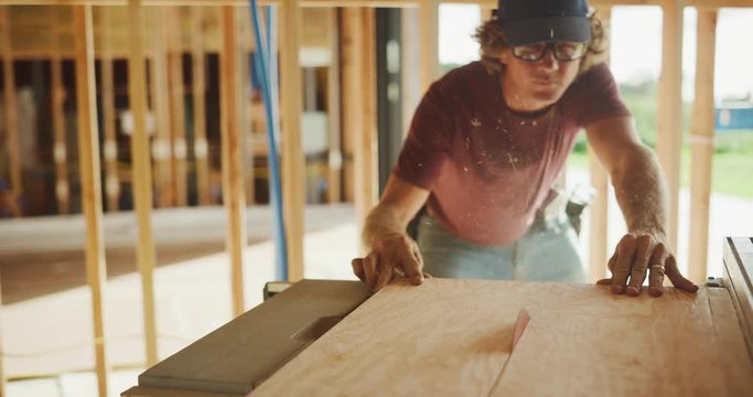 Carpenter expertly runs plywood through table saw