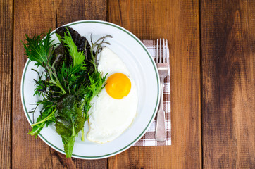 Plate of fried eggs and green salad leaves for breakfast