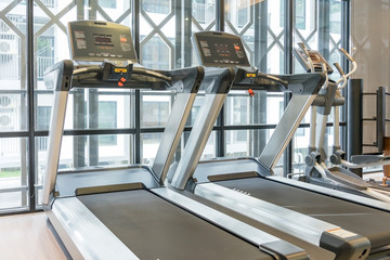 Treadmills set in gym interior. Fitness club with equipment. Sports background with glass windows