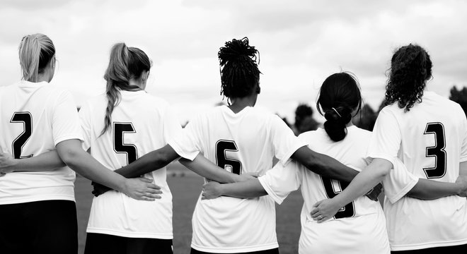 Female soccer players huddling and standing together