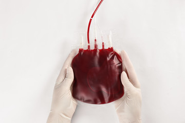 Doctor in gloves holding blood pack on white background, top view. Donation day