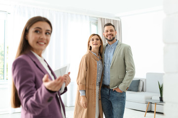 Female real estate agent showing new house to couple, indoors
