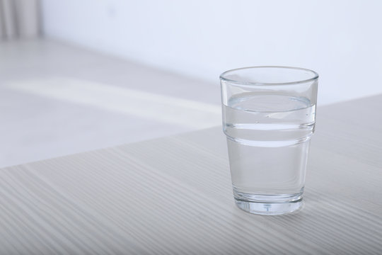 Glass of water on table against blurred background. Space for text