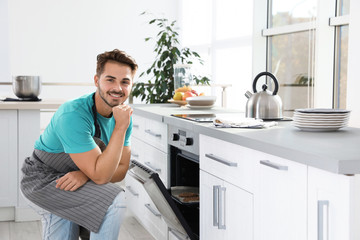 Young man baking cookies in oven at home