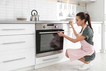 Fototapeta na wymiar Young woman baking something in oven at home