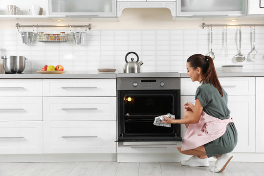 Young woman baking something in oven at home