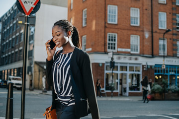 Woman on the phone while walking in the city - obrazy, fototapety, plakaty