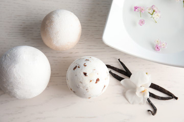 Flat lay composition with bath bombs and vanilla pods on white wooden background