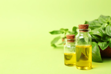Bottles of basil oil and leaves with space for text on color background