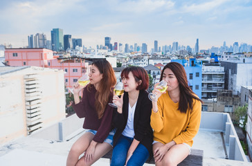 Fototapeta premium Happy group of asian girl friends enjoy laughing and cheerful sparkling wine glass at rooftop party,Holiday celebration festive,teeage lifestyle,freedom and fun.