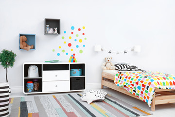 Modern child room interior with comfortable bed and striped carpet