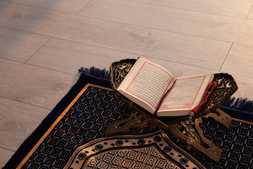 Rehal with open Quran and Muslim prayer beads on rug indoors. Space for text - obrazy, fototapety, plakaty