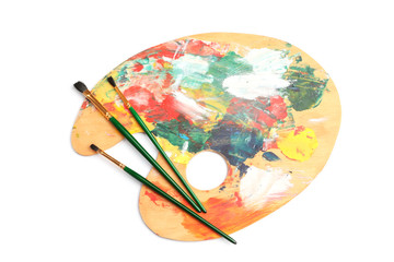 Wooden palette with brushes on white background, top view. Painting equipment for children