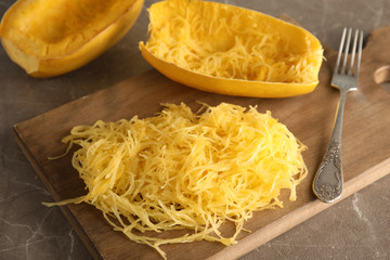 Cooked spaghetti squash and fork on wooden board