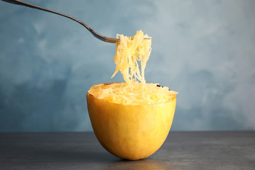 Fork with flesh over cooked spaghetti squash on table