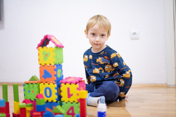 Preschooler child playing with colorful toy blocks. Kid playing with educational wooden toys.