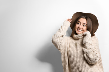 Beautiful young woman in warm sweater with hat on white background. Space for text