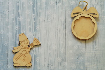 Vintage wooden toys. Snowman with broom and ball on gold cord on light background stylized snowflakes.