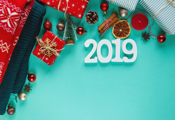 Christmas concept flat lay. Warm, cozy winter clothing and Christmas decorations frame on green background