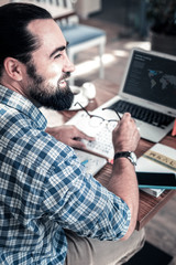 Look into window. Cheerful dark-eyed bearded man looking into window enjoying sunny day