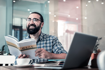 Excited man. Beaming cheerful bearded dark-haired man feeling excited while studying foreign...