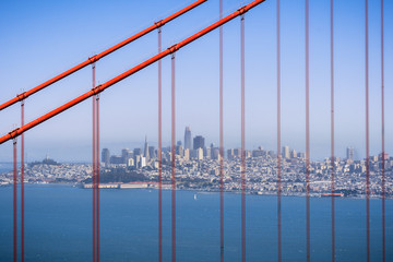 San Francisco's skyline viewed through the suspension cables of Golden Gate Bridge, California
