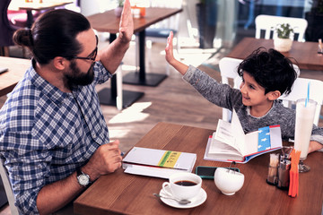 Preschool boy. Cute dark-eyed preschool boy giving high five his Chinese tutor after amazing...