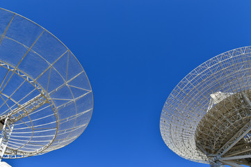 Array of satellite dishes or radio antennas against sky. Space o