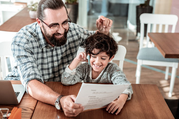 Restaurant with dad. Laughing cute son calling his mother while sitting in restaurant with his loving caring dad