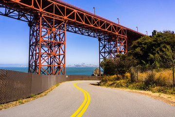 Road going under Golden Gate Bridge, the San Francisco skyline visible in the background; California