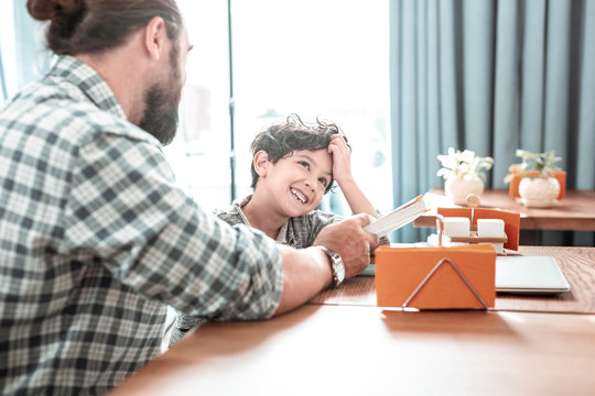 Day with father. Funny laughing dark-haired son feeling extremely happy spending day with father