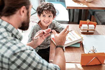 Cute preschooler. Private tutor wearing hand watch teaching little cute preschooler listening to him attentively