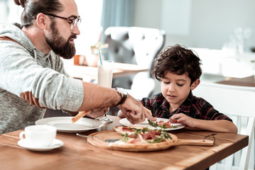 Fathers day. Father and son celebrating fathers day together eating yummy cheesy pizza in restaurant