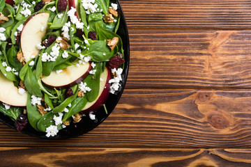Autumn spinach salad with apple , cheese , walnut and dried cranberry . Healthy vegetarian food