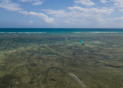 Kiteboarding, kite surf. Extreme sport kitesurfing in tropical blue ocean, clear beach. Aerial views, top view from drone of kitesurfing on the wave and beautiful sea. Kite surfer rides the waves