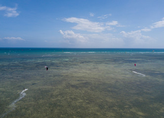 Kiteboarding, kite surf. Extreme sport kitesurfing in tropical blue ocean, clear beach. Aerial views, top view from drone of kitesurfing on the waves of the beautiful sea. Kite surfer rides the waves