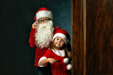funny brother and sister in Christmas costumes on dark background . Children waiting for Christmas