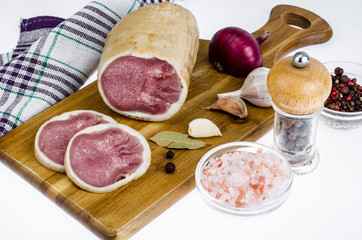 Smoked ham on wooden board, spices, kitchen napkin