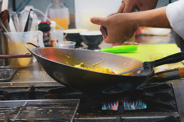 Chef cooking with flame in a frying pan on a kitchen stove, Chef in restaurant kitchen at stove with pan, doing flambe on food