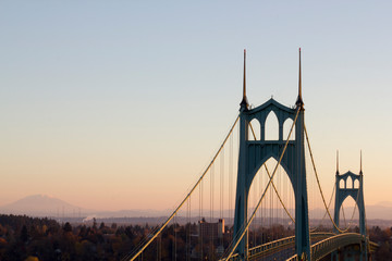 Portland's St. Johns Bridge at dawn with Mt St. Helens in the distance. With tall Gothic Cathedral Spires and graceful arches, it is the largest and most significant suspension bridge in Oregon.