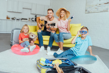 Obraz premium happy family holding passport, packing baggage for summer vacation and having great time, travel concept