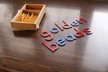 Golden Beads Spelled out with Box Behind