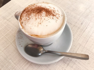 Cup of cappuccino with cinnamon on table