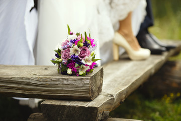 Wedding bouquet on the background of the feet of the newlyweds on the wedding day.