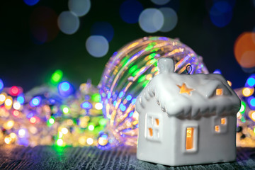 winter holidays decoration with small house, glass christmas ball and multicolor garland lights