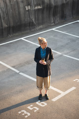 attractive fashionable girl with coffee to go standing on parking