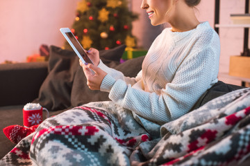 cropped view of woman sitting on couch and using tablet at christmas time